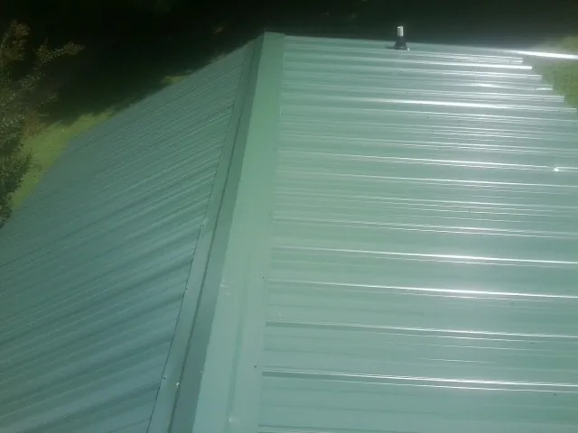 New green metal panels meeting at the ridge of a roof — Flat Roof Repair work by our crew in Mentone