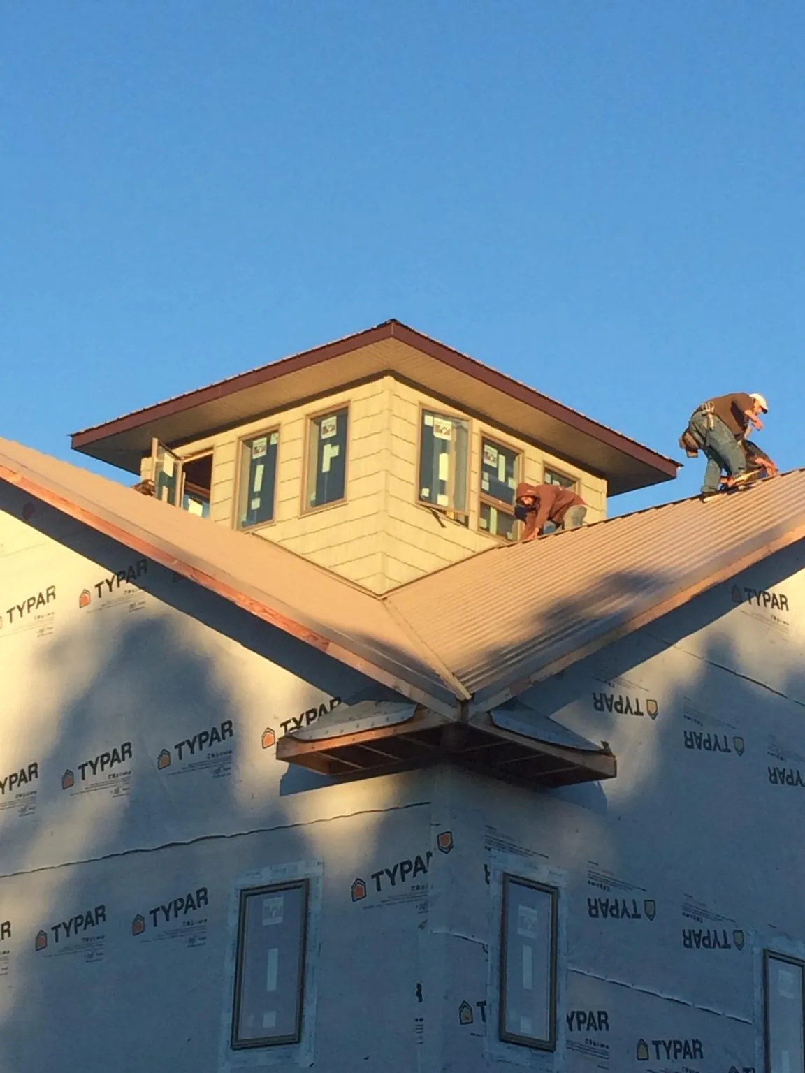 Roofers working around a rooftop cupola on a new metal roof at sunset — Roof Waterproofing in Mentone by Roofing Brothers